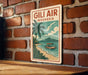 A vintage travel poster for Gil Air, Indonesia, featuring a palm tree, a boat on the water, and a beach scene.