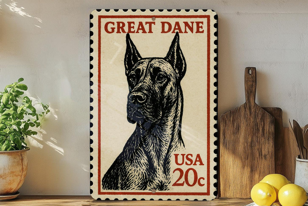 A framed postage stamp featuring a Great Dane dog, with the text "GREAT DANE" and "USA 20c" printed on it. The stamp is placed on a wooden surface, with a potted plant, a wooden cutting board, and some lemons nearby.