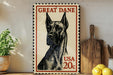 A framed postage stamp featuring a Great Dane dog, with the text "GREAT DANE" and "USA 20c" printed on it. The stamp is placed on a wooden surface, with a potted plant, a wooden cutting board, and some lemons nearby.