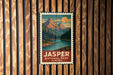 A vintage-style metal sign with a mountain landscape and a river, mounted on a wooden wall.