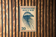 A vintage Portuguese postage stamp featuring an illustration of a jellyfish is displayed on a wooden wall.