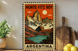 A vintage-style poster of the Monte Fitz Roy mountain range in Argentina, featuring a colorful illustration of the peaks and a lake.