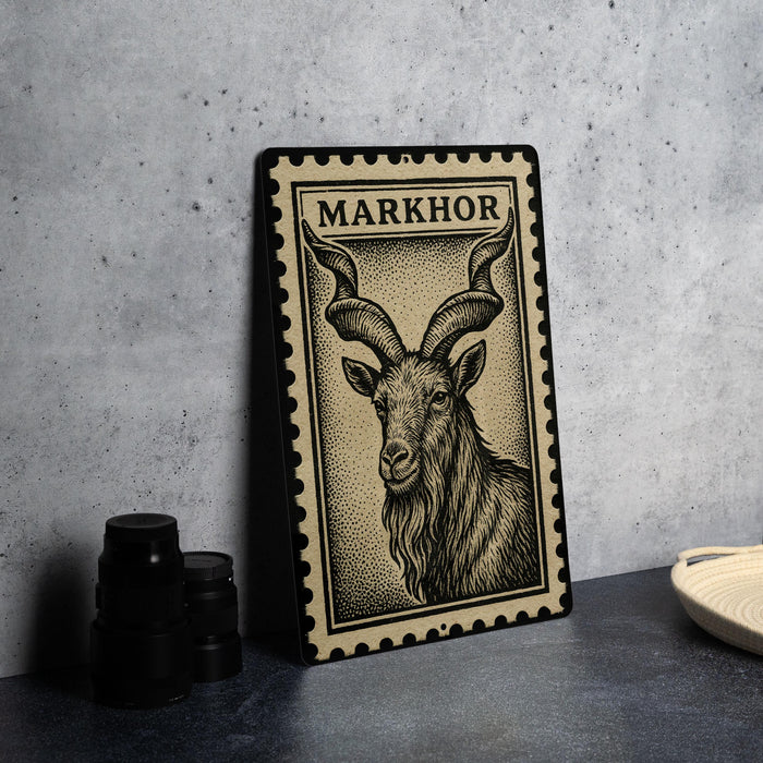 A metal plate with a black and white illustration of a horned animal, possibly a goat or ram, is displayed on a table.