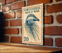 a vintage-style Portuguese postage stamp with an illustration of a jellyfish on it, mounted on a brick wall.