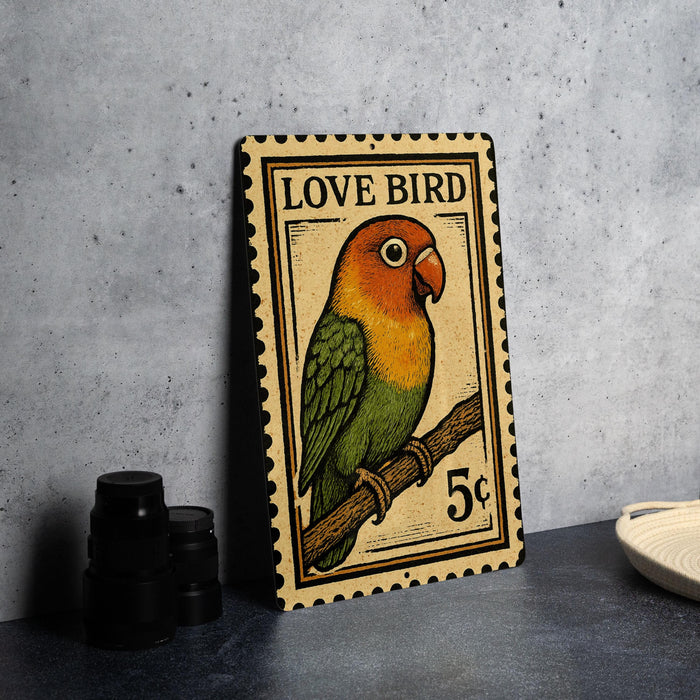 A metal stamp featuring a colorful parrot perched on a branch, with the text "LOVE BIRD" and "5¢" printed on it.