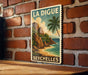 A vintage-style poster of a tropical island landscape, featuring a palm tree, mountains, and a beach, is displayed on a brick wall.