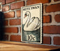 A vintage postage stamp featuring a swan on a brick wall.