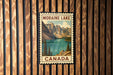 A vintage-style postage stamp depicting Moraine Lake in Canada, with a mountain landscape and a lake in the background.
