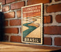 A vintage-style poster of the Lençois Maranhenses, a famous landmark in Brazil, is displayed on a brick wall.