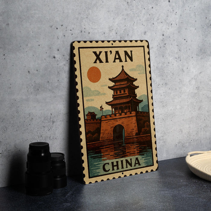 A vintage-style metal sign depicting a Chinese temple with a sun in the background, placed on a gray countertop next to some black camera lenses.