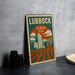 A vintage-style postage stamp from Texas, featuring a cityscape and a barn, is displayed on a table.