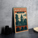 A vintage-style metal sign with the text "MANCHESTER ENGLAND" and an illustration of a city skyline, featuring a clock tower and a bridge.