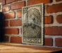 A wooden table with a wooden surface, and a framed image of a dog with a black and white pattern on the wall behind it.
