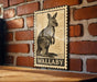 A wooden table with a framed illustration of a kangaroo on it, mounted on a brick wall.