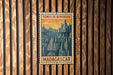 A vintage postage stamp from Madagascar, featuring a mountainous landscape with pine trees and a sunset sky.
