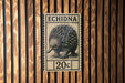 a postage stamp with an illustration of an echidna, which is a type of porcupine. The stamp is placed on a wooden wall.