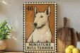 a miniature bull terrier, a small dog breed, displayed on a wooden surface.