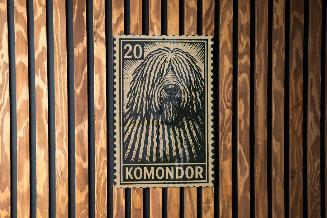 A black and white postage stamp featuring a close-up of a shaggy dog's head, with the word "KOMONDO" printed below it.
