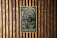 A black and white postage stamp featuring a close-up of a shaggy dog's head, with the word "KOMONDO" printed below it.