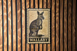 A wall-mounted metal sign featuring a kangaroo illustration and the word "WALLABY".