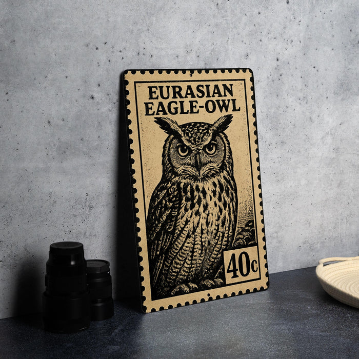 a metal stamp with an illustration of an owl, placed on a table next to some black camera lenses.