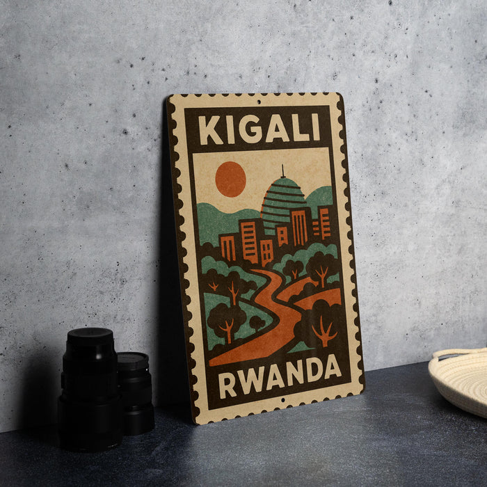 A vintage-style metal sign with the text "KIGALI RWANDA" and an illustration of a cityscape with a sun and mountains.
