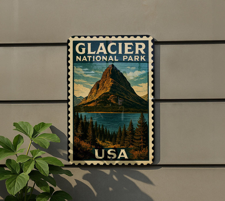 A vintage-style postage stamp featuring a mountain landscape with a lake, mounted on a wall next to a plant.