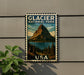 A vintage-style postage stamp featuring a mountain landscape with a lake, mounted on a wall next to a plant.
