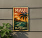 A vintage-style metal sign with the text "MAUI HAWAII USA" displayed on a wall, featuring a palm tree and ocean landscape.