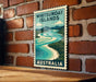A vintage-style poster of the Whitsundays, a collection of islands in Australia, is displayed on a brick wall.