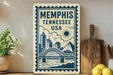 A framed sign displaying the text "Memphis, Tennessee, USA" along with a graphic of a bridge and city skyline.