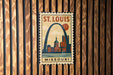 A vintage-style metal sign with the text "ST. LOUIS MISSOURI" and an illustration of the Gateway Arch, a famous landmark in St. Louis, Missouri.