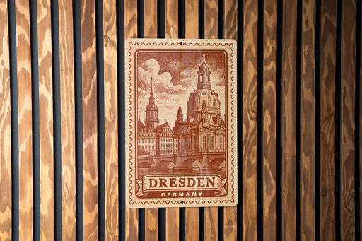 A postage stamp featuring the Dresden Cathedral in Dresden, Germany, is displayed on a wooden wall.
