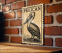 A wooden surface with a framed image of a pelican on it, mounted on a brick wall.