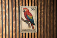A postage stamp featuring a colorful parrot, specifically a red and blue macaw, perched on a branch.