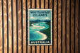 A vintage-style postage stamp depicting the Whitsunday Islands in Australia, with a river and mountains in the background.
