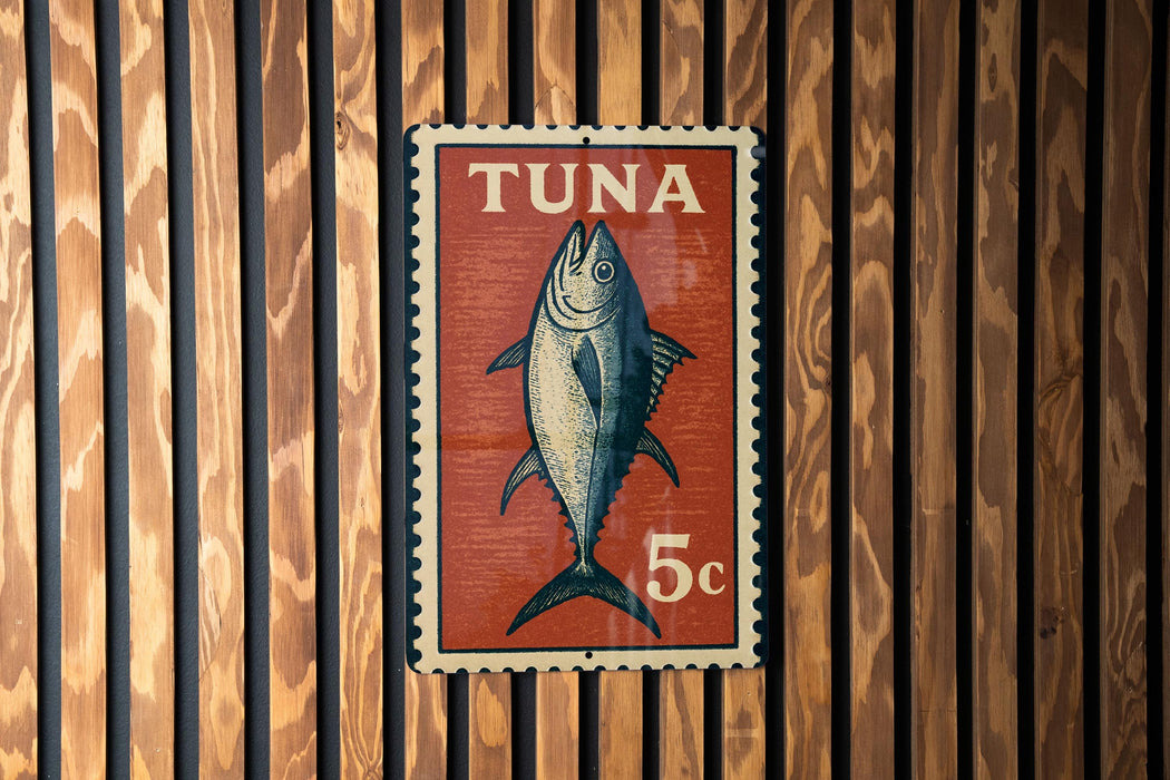 A red and white sign with a fish illustration, mounted on a wooden wall.