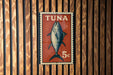 A red and white sign with a fish illustration, mounted on a wooden wall.