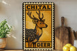 a decorative metal sign with a deer illustration, placed on a wooden surface next to a wooden cutting board and some lemons.