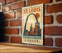 A vintage-style metal sign depicting St. Louis, Missouri, with the city's skyline and iconic arch in the background.