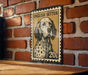A metal sign featuring a dog's portrait, mounted on a brick wall.