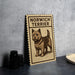 a wooden sign with a drawing of a dog, specifically a terrier, and the text "NORWICH TERRIER" printed on it.