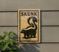a sign with a skunk illustration on it, mounted on a wall next to a plant.