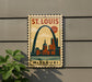 A vintage-style metal sign with the text "ST. LOUIS MISSOURI" and an illustration of the Gateway Arch in St. Louis, Missouri.
