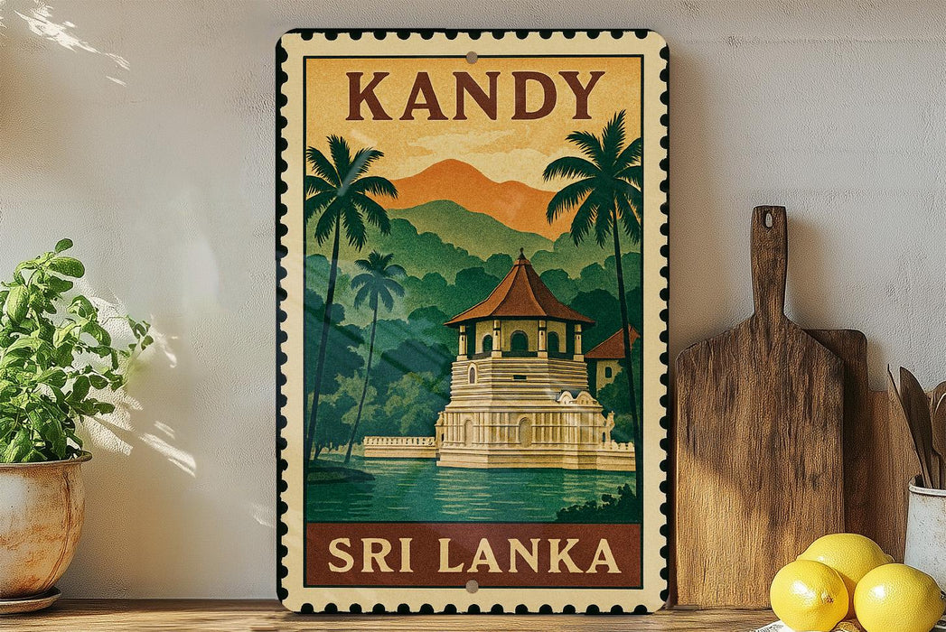 A vintage-style metal sign with a tropical landscape depicting a temple, surrounded by palm trees and mountains, with the text "KANDY" and "SRI LANKA" printed on it. The sign is displayed on a shelf next to a wooden cutting board and a potted plant.