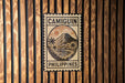 a sign with the word "CAMIGUIN" and "PHILIPPINES" printed on it, mounted on a wooden wall.