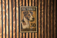 A metal stamp featuring a fox terrier dog with the number 30 on it, mounted on a wooden wall.