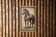 a wooden wall with a framed illustration of a horse.