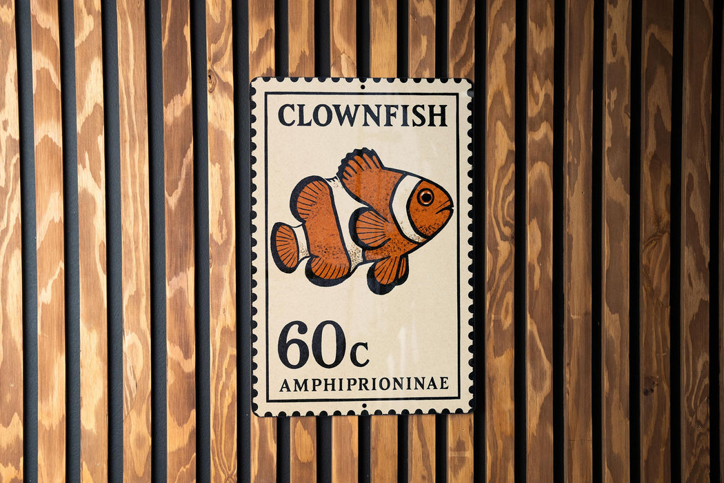 A metal sign with a clownfish illustration and the text "CLOWFISH" and "60c AMPHIPRIONINAE" printed on it.
