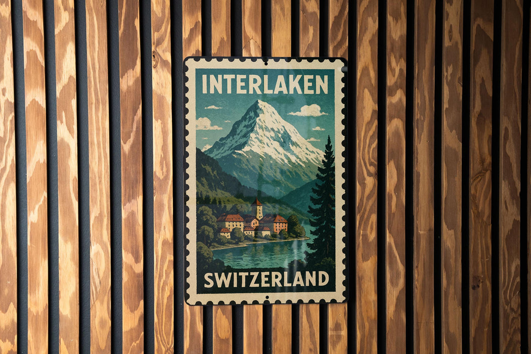 A vintage-style metal sign with the text "INTERLAKEN SWITZERLAND" and an illustration of a mountain landscape with a village in the background.